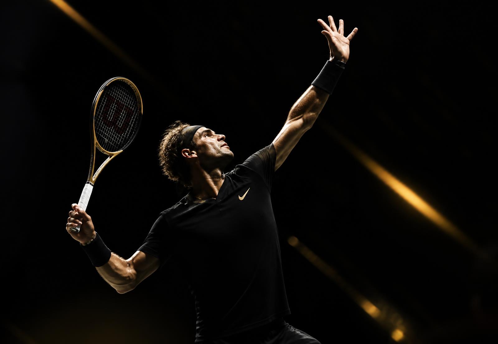 Competitive tennis player striking a serve during an intense night training session